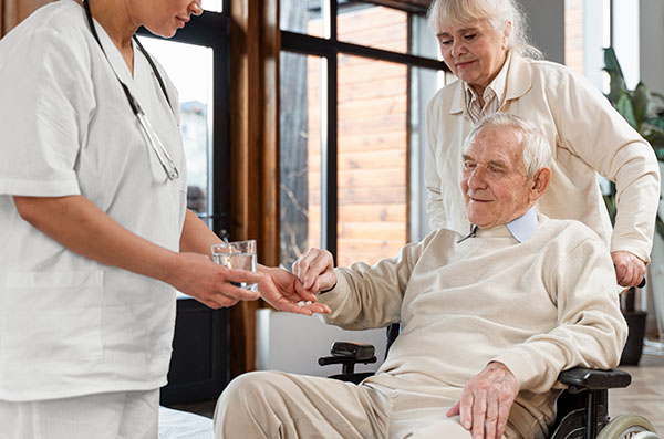 man in wheelchair getting medication from nurses